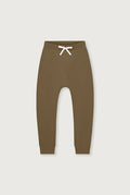 A pair of solid brown jogger-style pants with a white drawstring at the elastic waistband, shown flat against a light gray background.