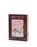 A 1000-piece jigsaw puzzle box titled 'Luna Puzzle' by Chic Chic, featuring a winter garden illustration on a dark brown background with a pink window view.