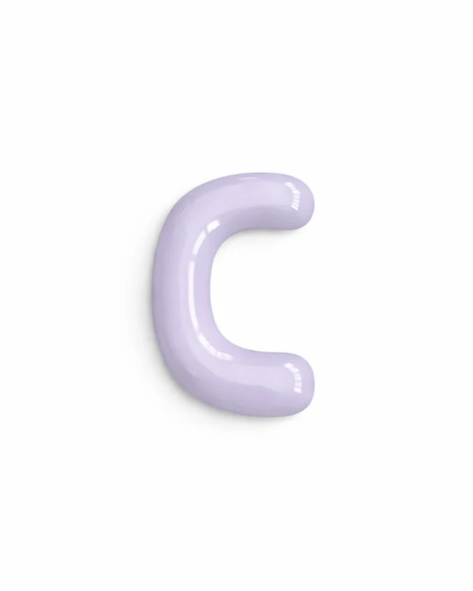 A glossy, lavender-colored letter 'C' shaped object, possibly a decorative letter tile or small sculpture, centered on a plain white background.
