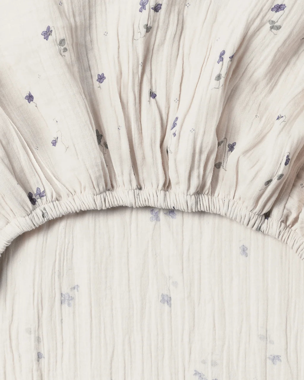 Close-up of a fitted sheet with subtle floral pattern on a plain background