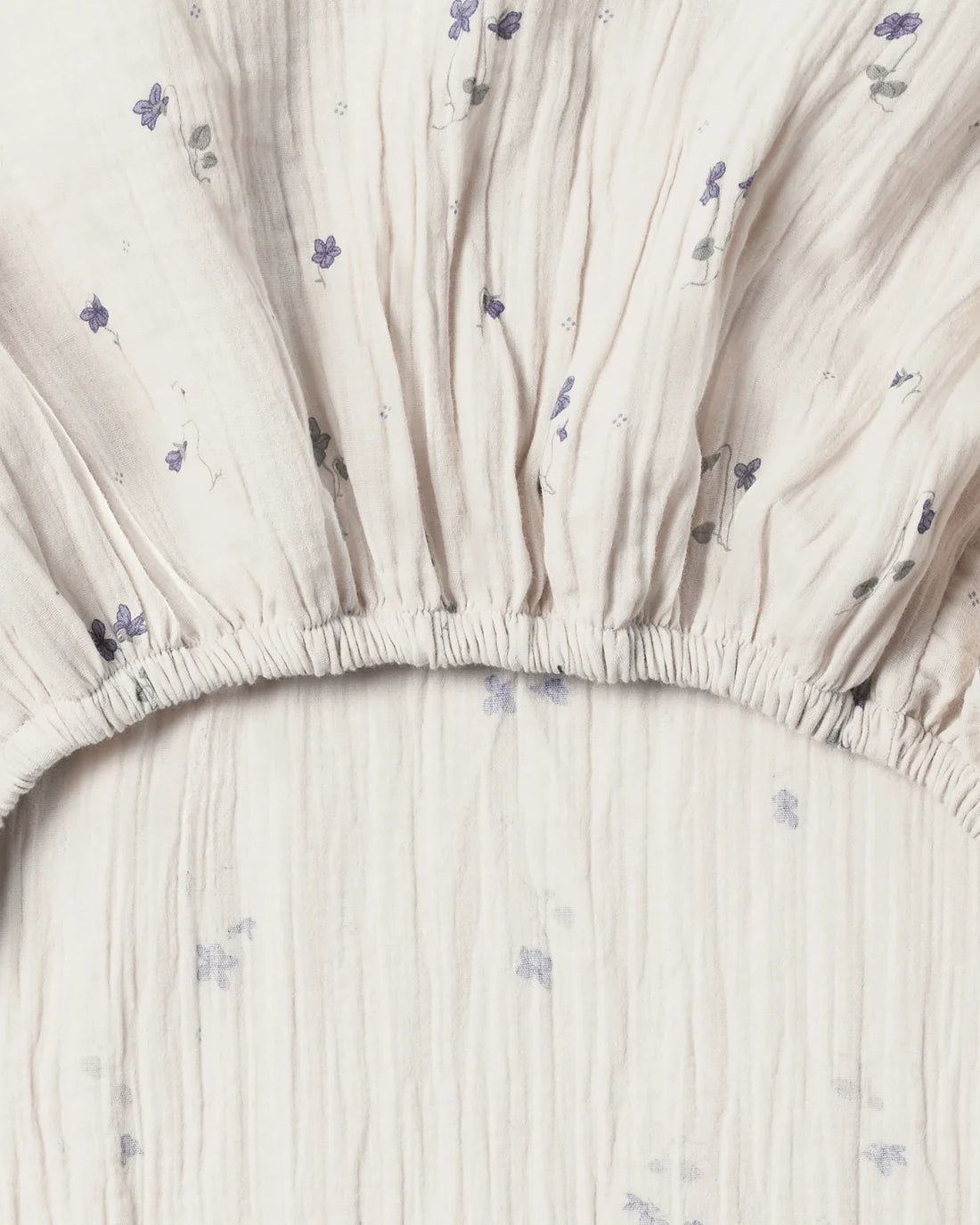 Close-up of a fitted sheet with subtle floral pattern on a plain background