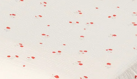 An off-white fitted sheet with a small red cherry print, shown on a mattress against a plain white background.