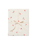 A gift-wrapped package featuring textured cream wrapping paper with a red and white floral pattern, tied with a matching cream satin ribbon in a bow, set against a plain white background.