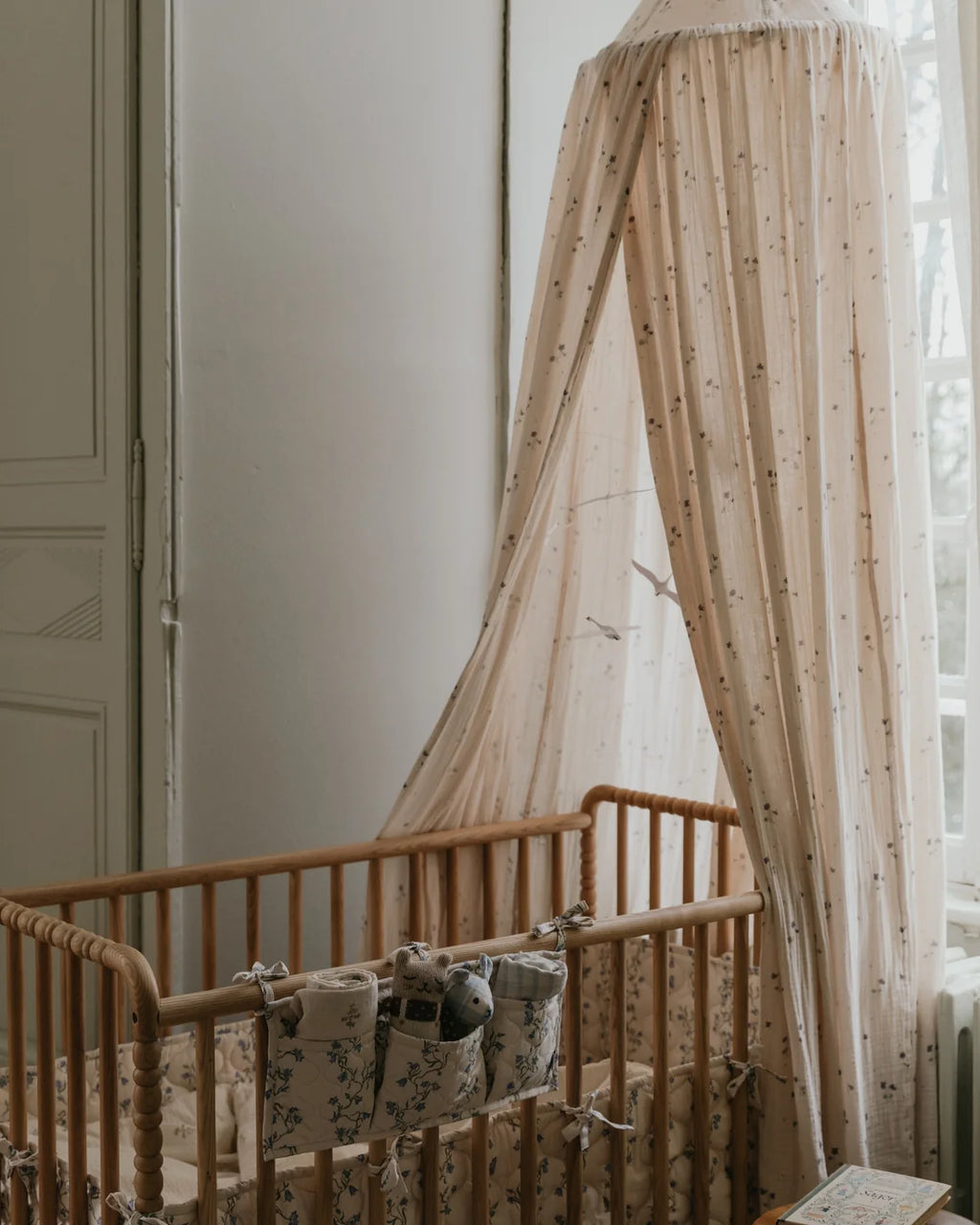 Wooden crib with canopy and baby blankets in a softly lit room.