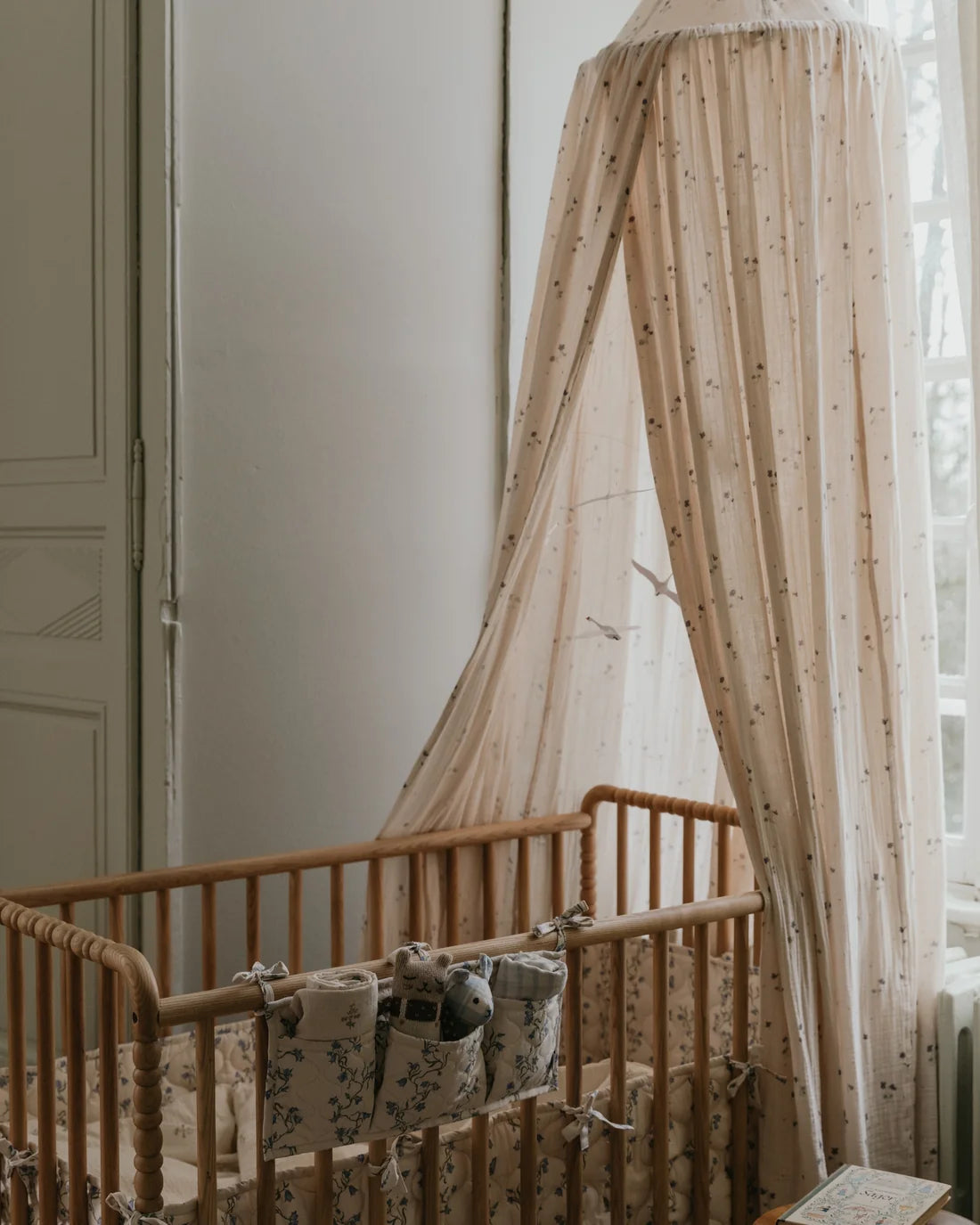 Wooden crib with canopy and baby blankets in a softly lit room.