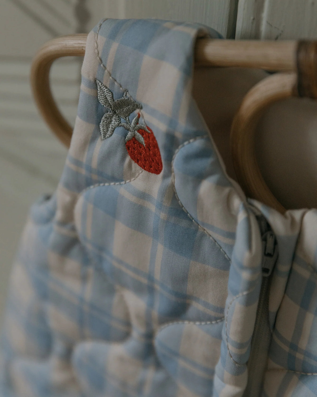 Blue plaid baby blanket with strawberry embroidery on a wooden surface