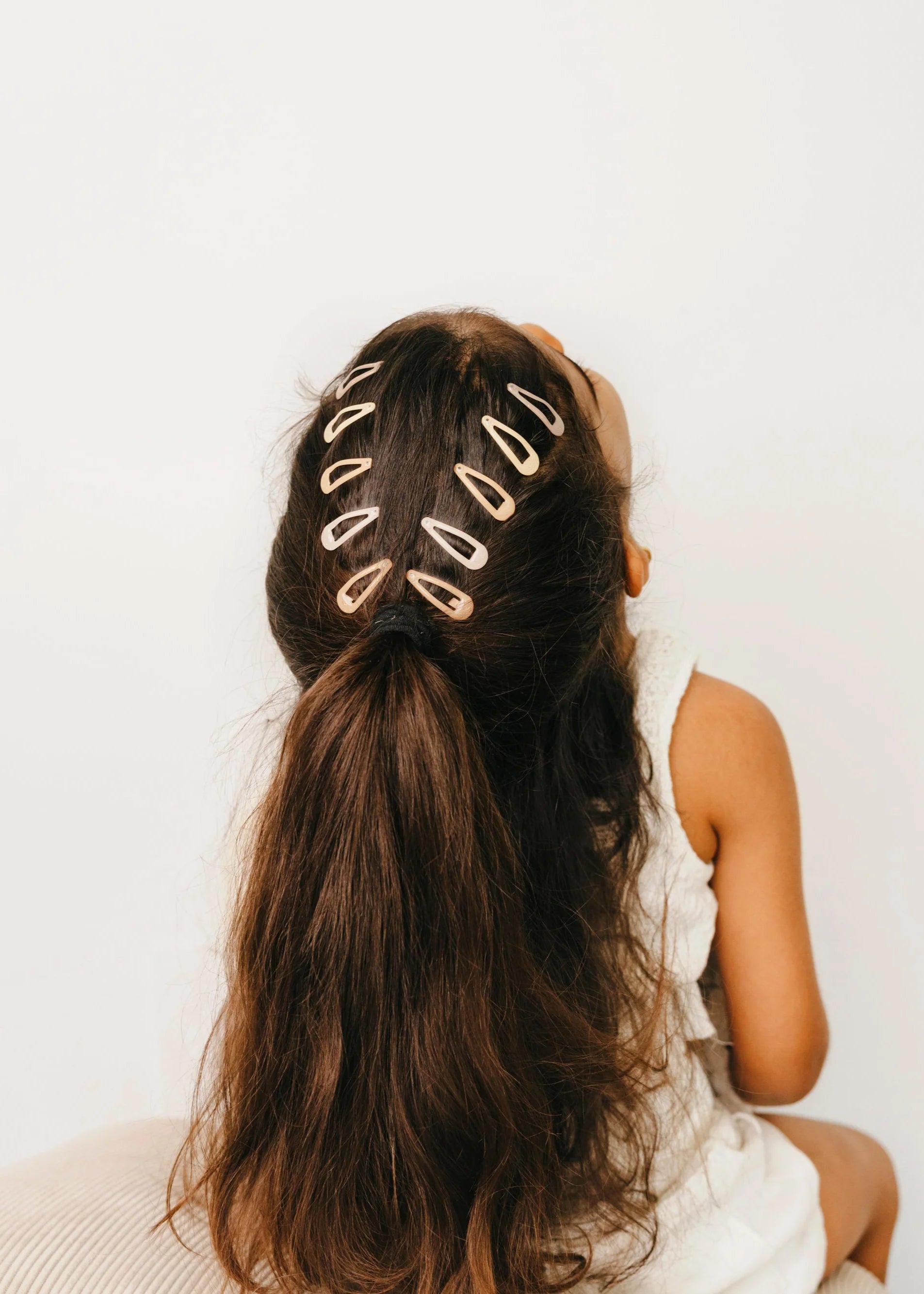 Person with long hair styled with gold hair clips on a plain background