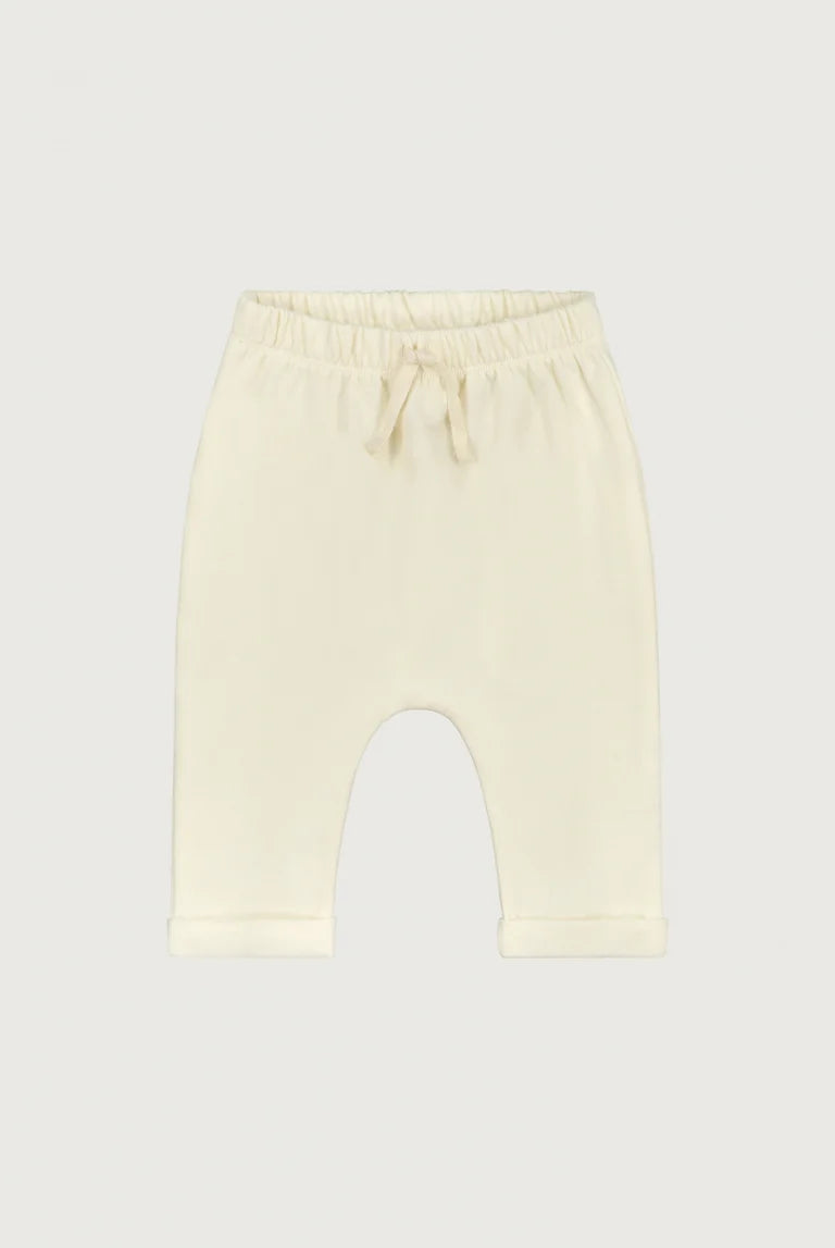 Cream-colored knit baby pants with an elastic waistband and drawstring, shown flat on a light gray background.
