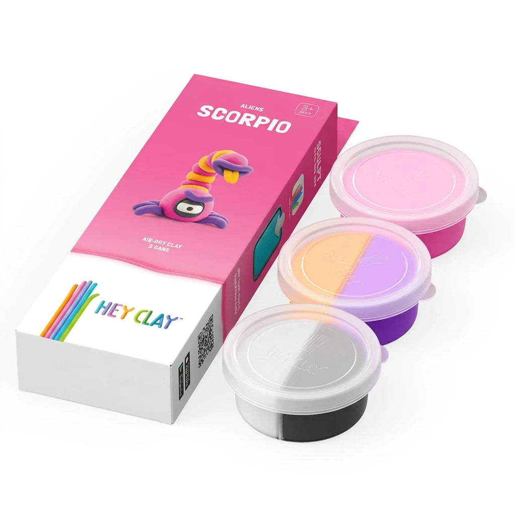 A box of Hey Clay lip clay along with three small round clay pots with translucent lids, shown on a clean white background. The box is pink with a cartoon character and the word 'SCORPIO', and the pots contain pastel pink, peach-purple, lavender, black, and white clay.