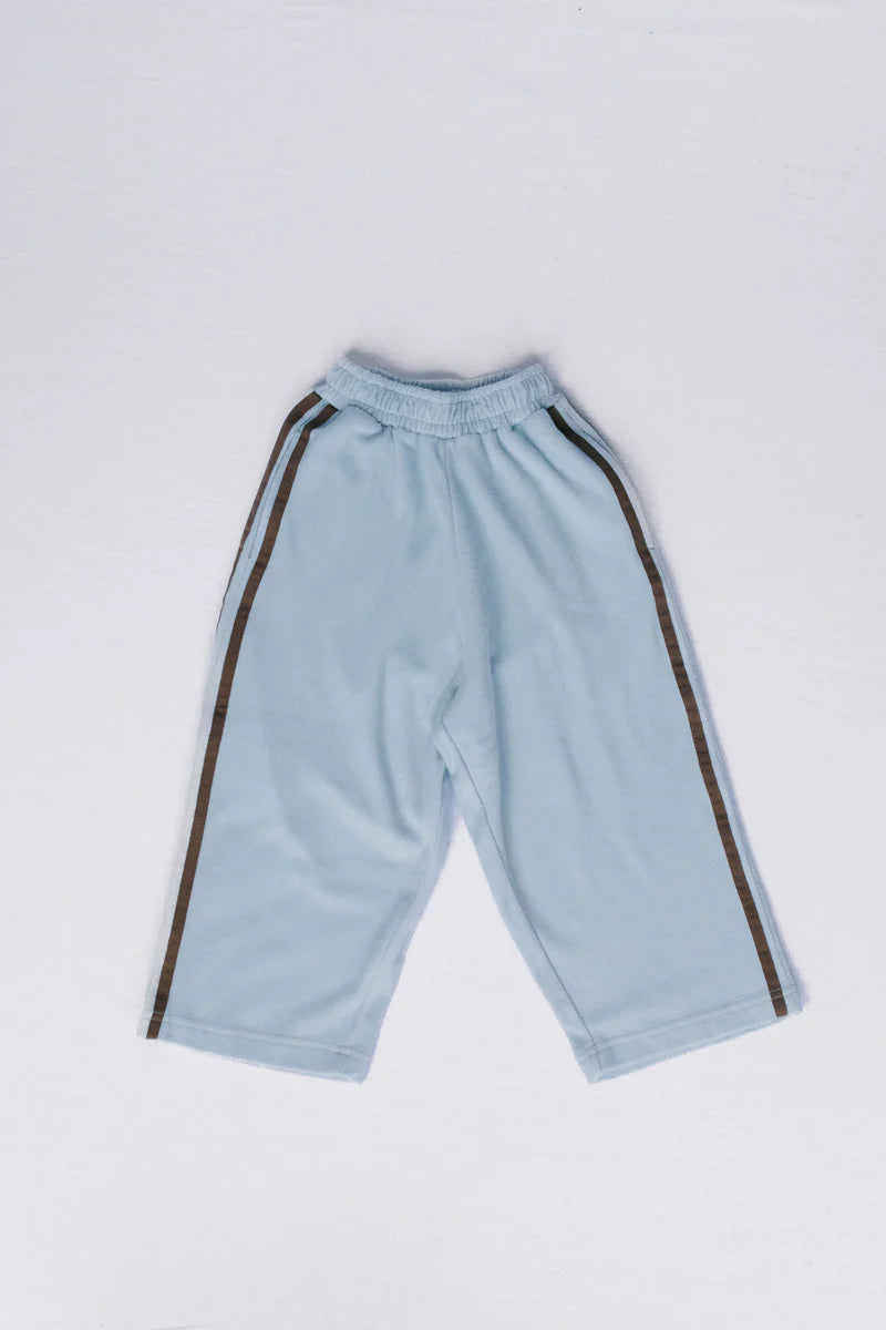 Light blue athletic pants with dark brown side stripes, laid flat on a light gray background.