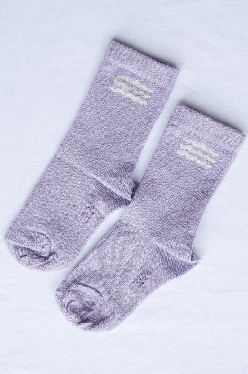 Pair of purple socks with a logo on a light gray background