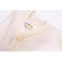 Close-up of a baby cardigan sweater in a soft cream color, featuring a ribbed collar, a single wooden button, and a colorful 'huhu' brand tag.