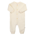 Cream-colored baby onesie with buttons on a white background