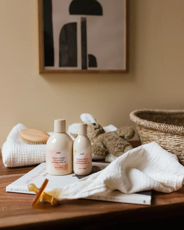 Two bottles of natural cleaning products on a wooden surface with a basket and cleaning tools in the background.
