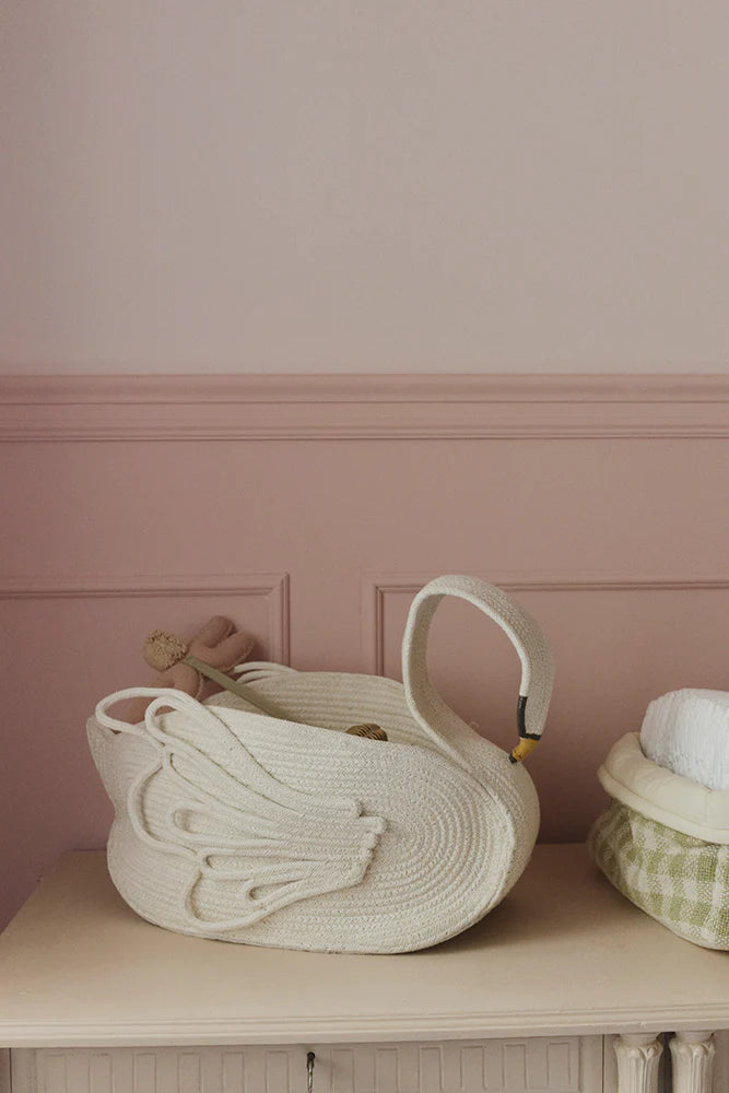 Woven Swan basket on a wooden surface with a pink wall background