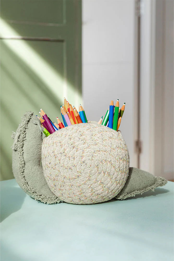 snail -shaped pencil holder with colorful pencils on a light surface.