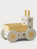 A minimalist wooden toy truck with a cream-colored body, a pale yellow cargo bed, and matching pale yellow details on the wheels and smokestacks, photographed on a light gray background.