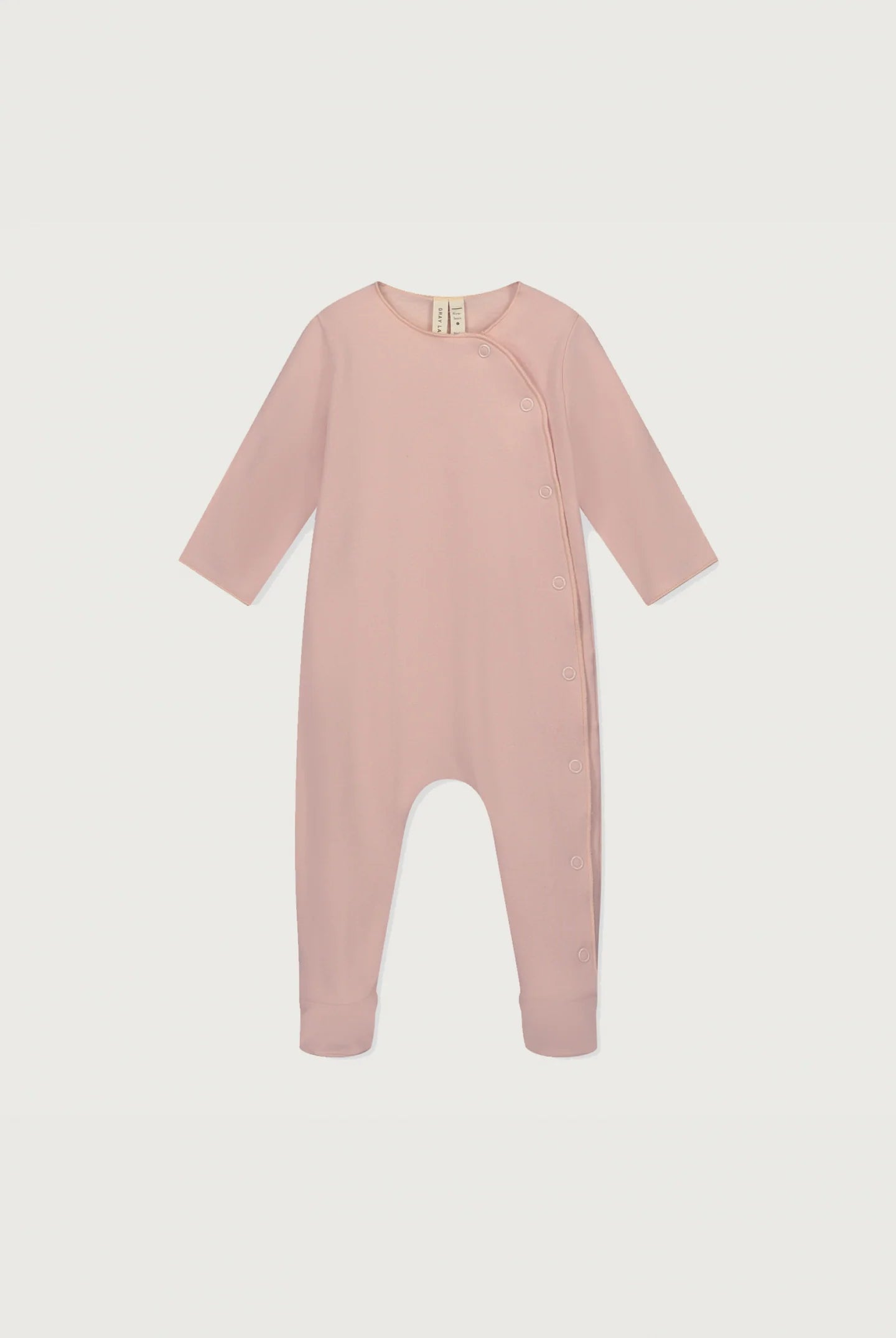 A baby long-sleeve footless jumpsuit in dusty pink, featuring an asymmetrical snap closure at the neckline, shown against a light gray background.