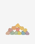 A set of small wooden heart-shaped blocks in pastel colors, stacked in a low arch on a plain light gray background.