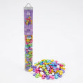 A tall clear plastic tube filled with colorful interlocking puzzle pieces stands next to a spilled pile of the same pieces on a white background. The tube label reads 'PASTEL'.