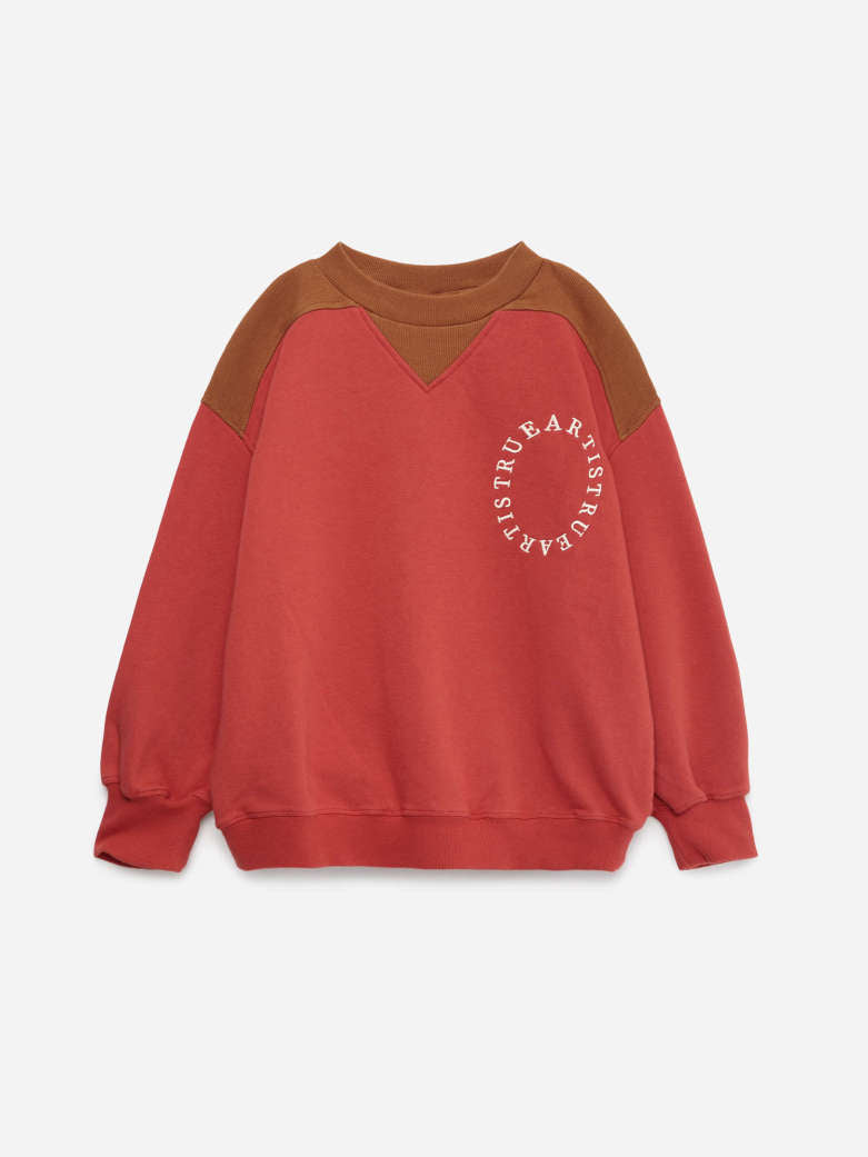A colorblock crewneck sweatshirt in red and brown, featuring a circular white graphic print on the left chest that reads 'TRULF BEARSTREY'.