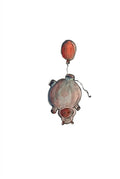 A watercolor art print of a hippo holding a red balloon, displayed on a brown kraft paper envelope over a wooden table.