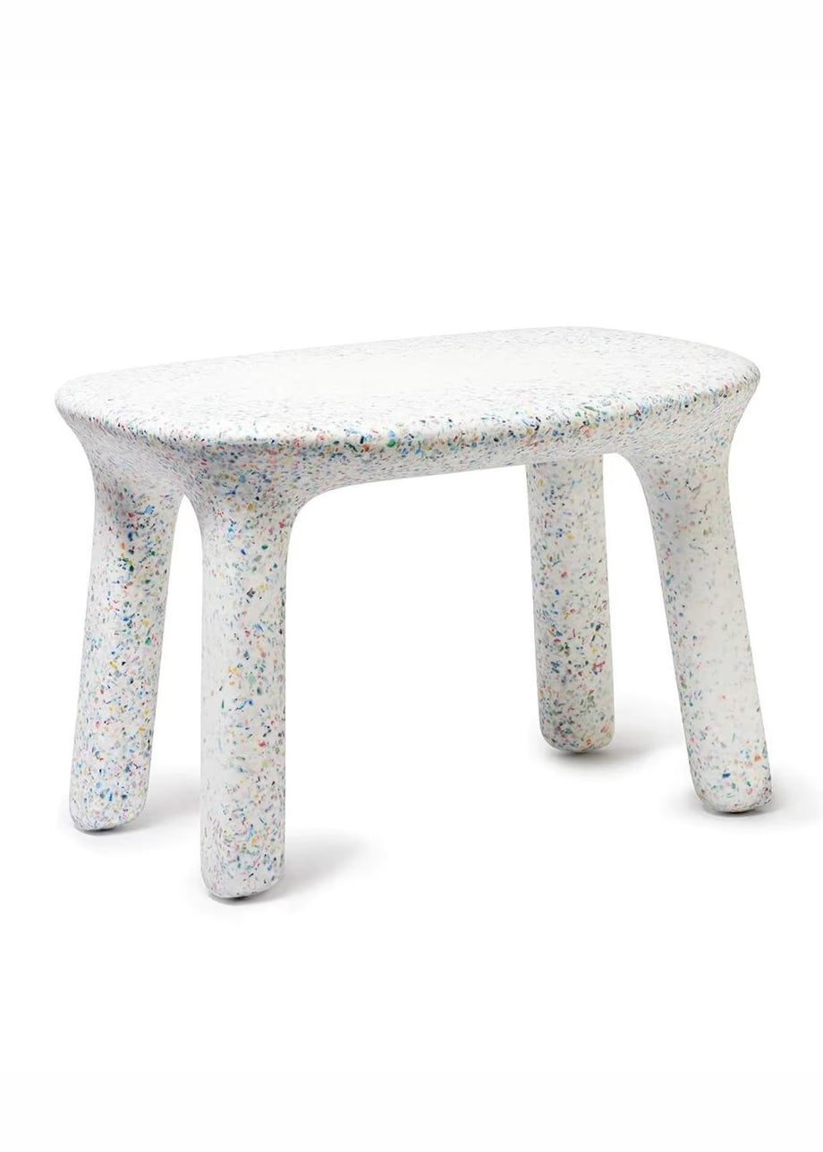 A table with a rounded rectangular and four legs, featuring a white speckled resin finish with multicolored flecks, shown on a white background.