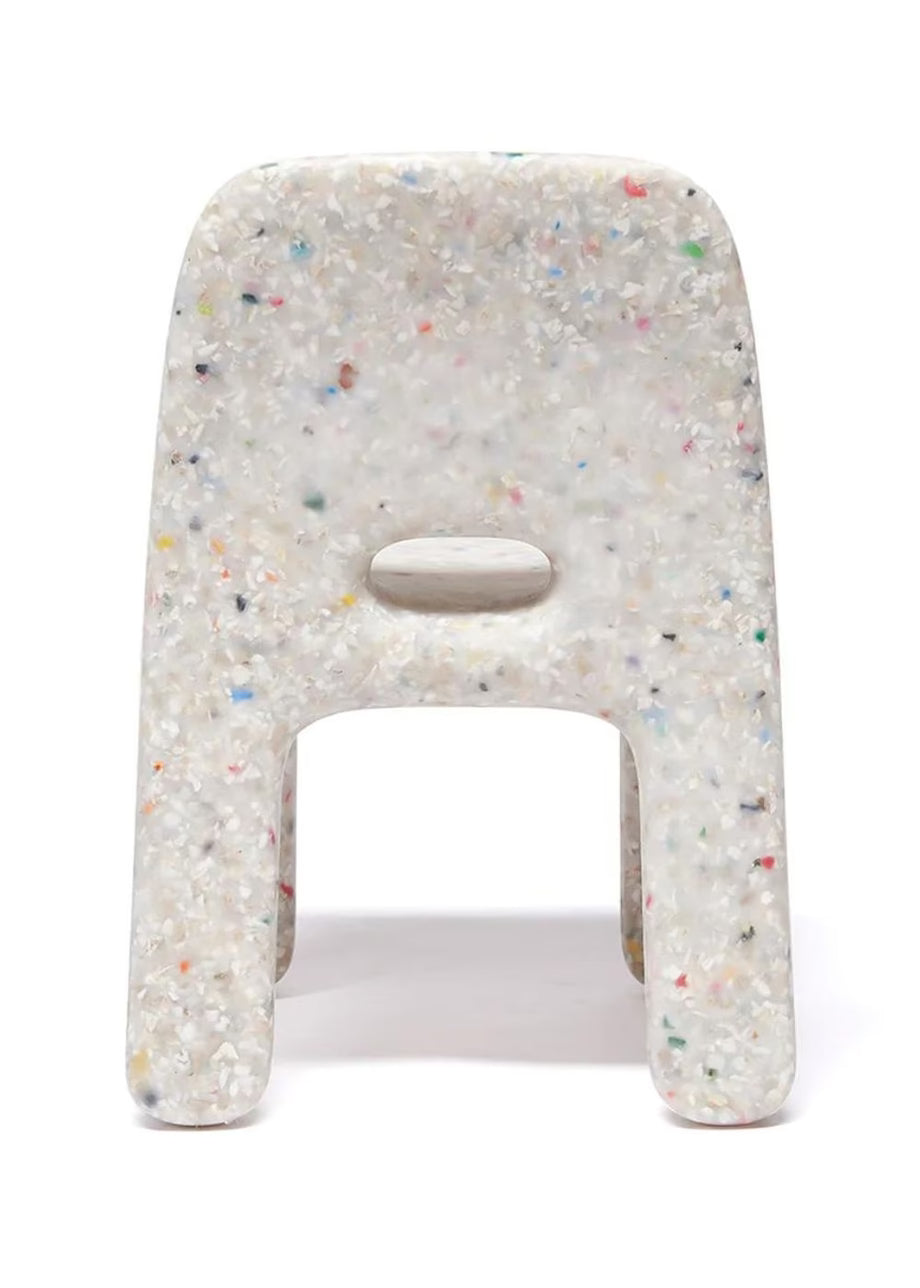 The chair has a cutout in the center of the backrest and is photographed on a seamless white background.multicolored flecks, featuring a central cutout handle, shown on a white background.