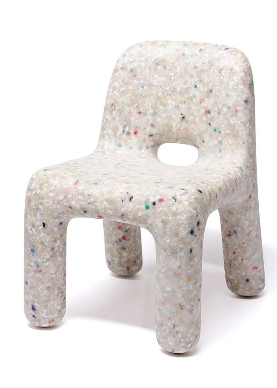 A small molded chair with a speckled translucent resin finish, featuring a cutout in the center of the backrest, shown on a plain white background.