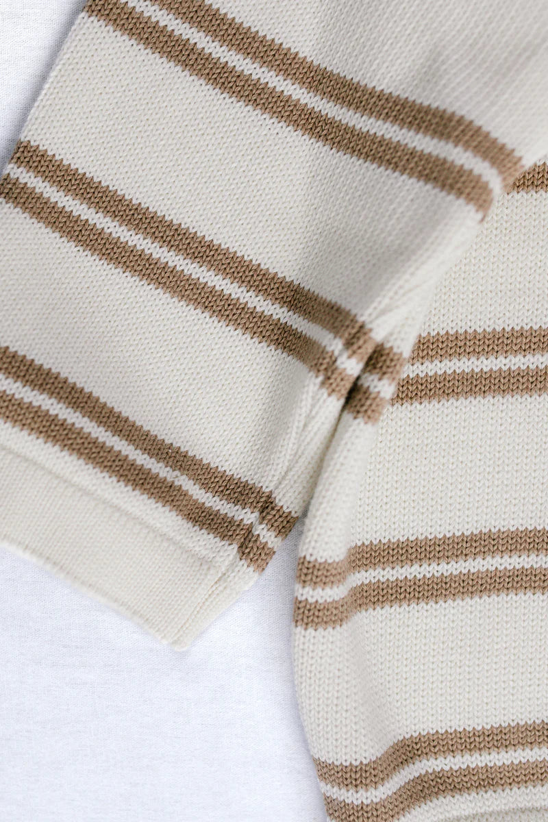 Close-up of a knit fabric with horizontal stripes in brown and white, showing the texture and pattern detail.