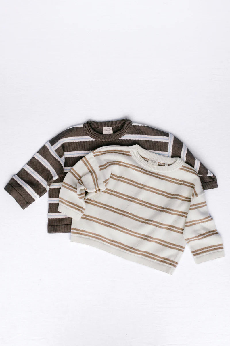 Two children's long-sleeve knit sweaters with horizontal stripes, laid flat on a white background. The sweater in the back is dark brown and cream, and the sweater in the front is off-white and light brown.