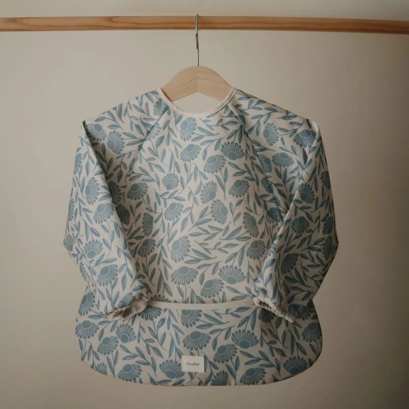 Floral patterned bib on a wooden hanger against a plain background