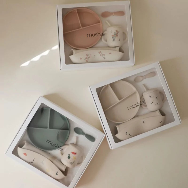Three sets of children's tableware in packaging on a light surface