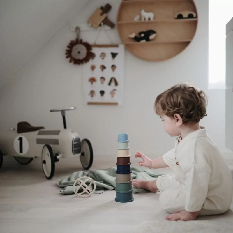 Child playing with toy stack in a room with toys and decor on the wall.