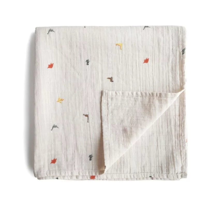 A folded muslin baby blanket in a warm off-white/cream color, featuring a small scattered print of various animal silhouettes in muted red, yellow, and gray. The blanket is shown on a clean white background with a soft drop shadow.